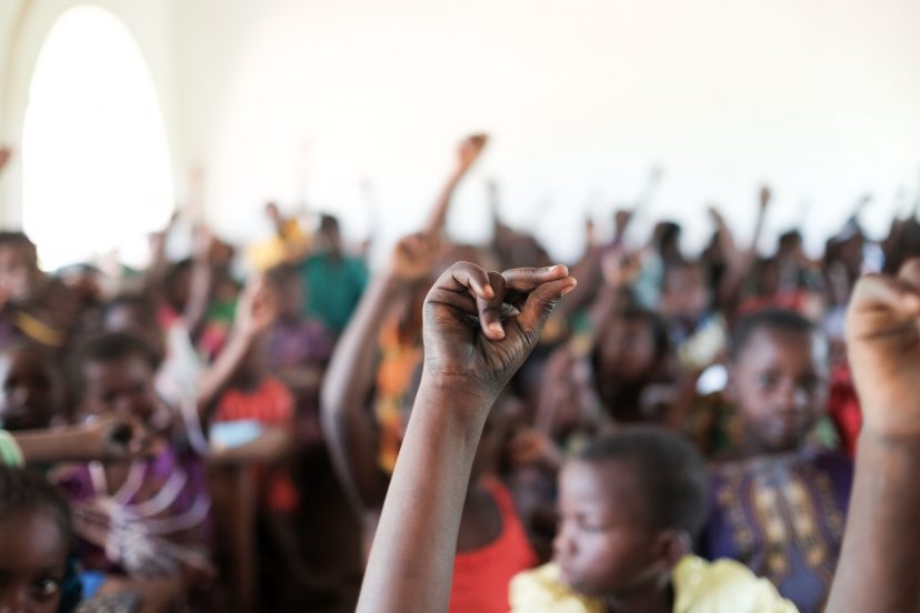 Koululuokka Keski-Afrikan tasavallassa, jossa usea lapsi on nostannut kätensä ylös.
