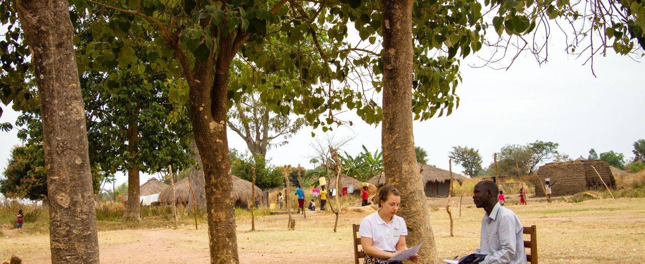 TwB volunteer Saara Turunen giving feedback after lesson observation to P6 teacher Onzima Sirati Sebbi outside Bamure Primary School in Koboko.