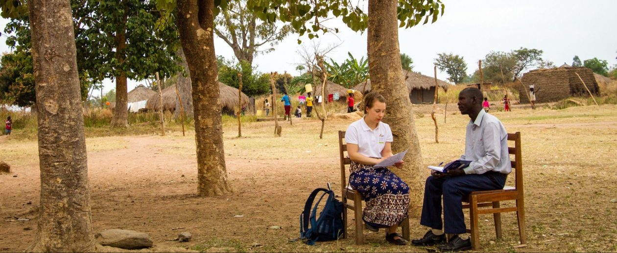 TwB volunteer Saara Turunen giving feedback after lesson observation to P6 teacher Onzima Sirati Sebbi outside Bamure Primary School in Koboko.