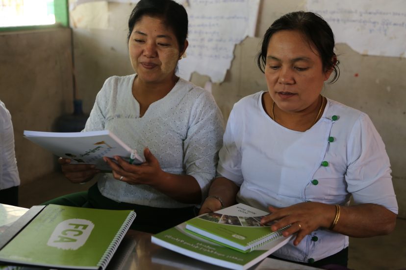 Kaksi myanmarilaista naista tarkastelee heidän edessän olevia kirjoja.