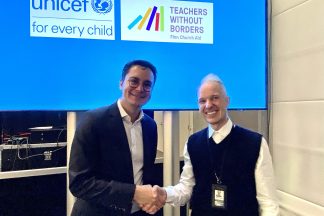 Two men shaking hands in front of the screen displaying logos of UNICEF and Teachers Withous Borders/Finn Church Aid